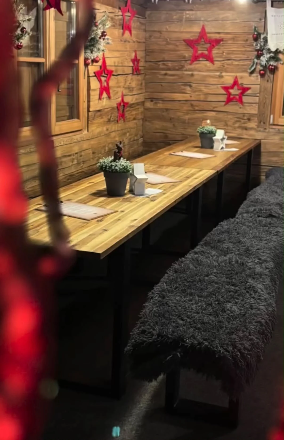 Gemütlicher Holztisch mit Bänken und rustikaler Dekoration in der Haldenzauber Almhütte